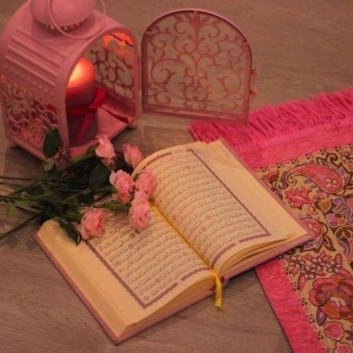 An open book with pink roses, a lantern, and patterned fabric on a wooden surface