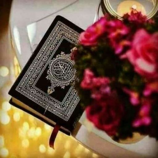 An ornate Quran book beside a bouquet of roses with soft bokeh lights in the background