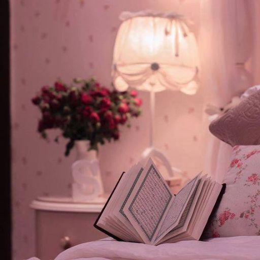 Cozy bedroom with an open book on the bed, a lamp and flowers in the background