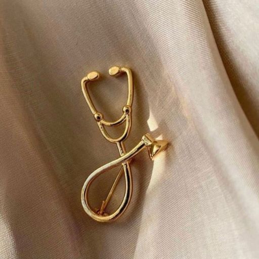 Gold stethoscope-shaped earring on a silky beige fabric