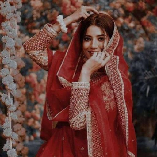 Person in a red embroidered outfit with a matching headscarf, posing against a floral background