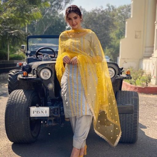 Person in traditional attire standing in front of a classic black jeep