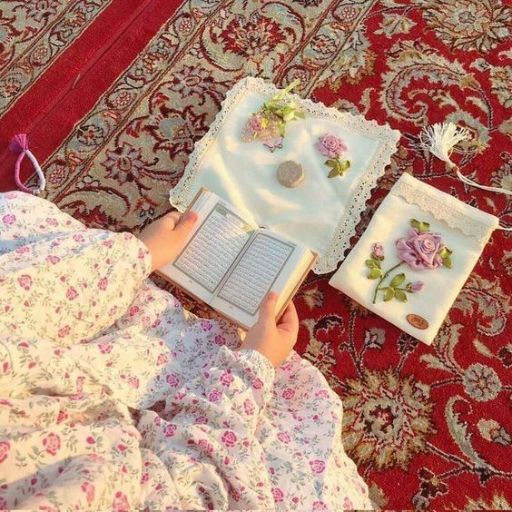 Person reading a book on a floral blanket with a decorated notebook beside them