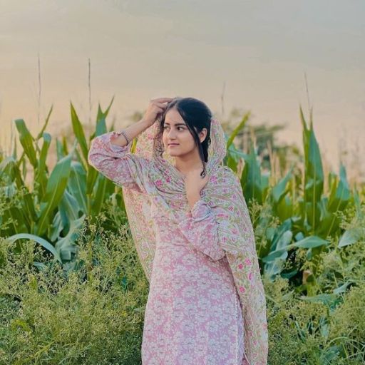 Woman in a floral dress standing in a field with corn plants in the background